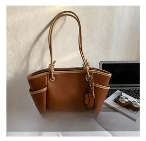 Detailweergave van bruine shopper met contrastbiezen en lederen bloemenhanger