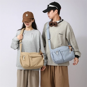 Detail of khaki and light blue crossbody bags featuring nylon texture and zip pockets