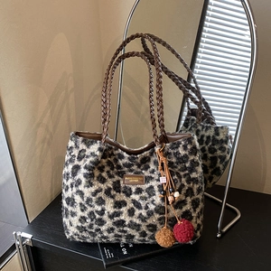 Detail of plush leopard print tote bag with woven handles and furry charm accessory