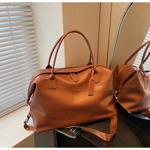 Detailed view of the large brown travel tote bag with leather texture and nylon strap