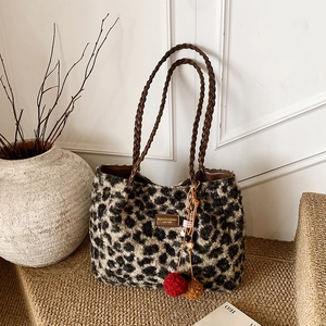 Detailed view of leopard print plush tote bag with braided handles and pompom charm