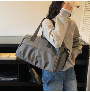 Detail of dark grey travel bag showing shoe compartment and padded shoulder strap