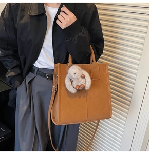 Brown faux leather tote bag detail with adjustable shoulder strap and bunny pendant