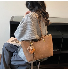 Brown vintage wax leather tote bag with teddy charm shown on shoulder for daily commute