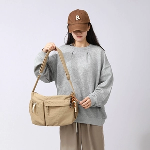 Detail of khaki large capacity crossbody bag with multiple pockets and wooden bead charm