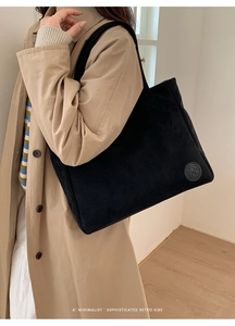 Macro shot of black corduroy tote bag showing textured fabric and side leather logo detail