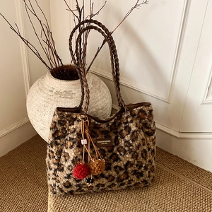 Detailed view of leopard print plush tote with braided straps and fluffy pom charms