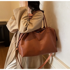 Brown large capacity leather travel tote bag with shoulder strap shown on a model