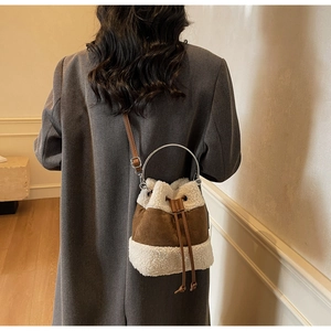 Detail of plush drawstring bucket bag showing brown suede and white fleece textures