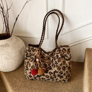 Detail of leopard print faux fur tote with woven leather straps and fuzzy pompom charm