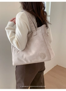 Detail view of large beige tote bag in matte finish showing strap and embossed logo