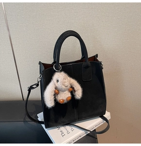 Detail of black matte leather mini tote bag with cute plush rabbit charm and strap