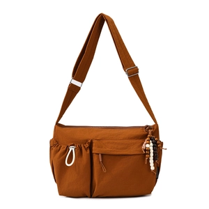 Close-up of brown crossbody bag featuring multiple pockets and unique wooden bead charm