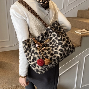 Detail of plush leopard print tote bag with woven leather handle and colorful pompom charms