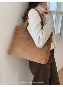 Detail of brown suede tote bag featuring a minimalist rectangular design and wide shoulder strap