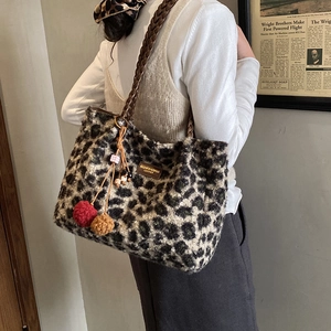 Detail view of large leopard print faux fur tote bag with braided strap and pompom charm