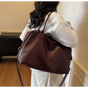 Macro detail of large burgundy PU leather travel tote showing handles and shoulder strap