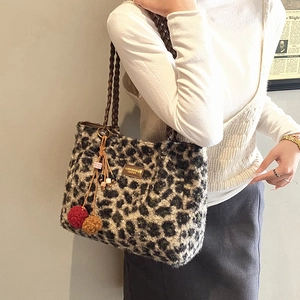 Detail of leopard print plush tote bag with woven brown handle and faux fur texture
