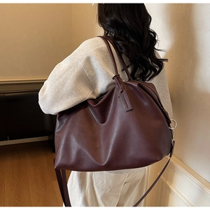 Detail view of large burgundy leather tote bag showing matte texture and logo tag