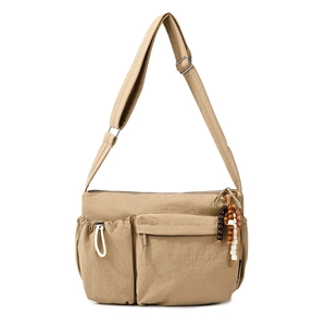 Detail showing the multi-pocket khaki nylon crossbody bag with wooden bead charm detail