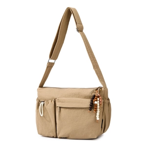 Close-up of khaki nylon tote bag featuring a beaded zipper pull and drawstring side pocket