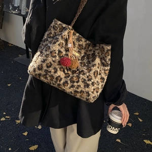Detailed shot of leopard print plush tote bag with furry charms on an autumn street