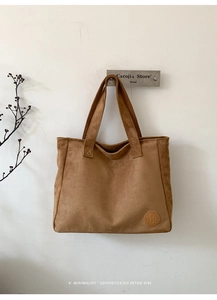Detail of brown suede tote bag with circular embossed logo and minimalist retro texture