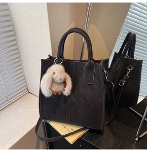 Close-up of a large coffee tote bag with suede texture and a cute white bunny charm