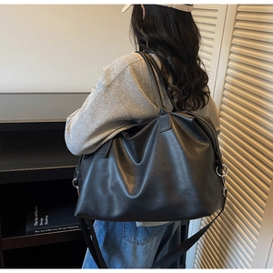 Close-up of matte black leather tote bag showing large capacity and adjustable strap