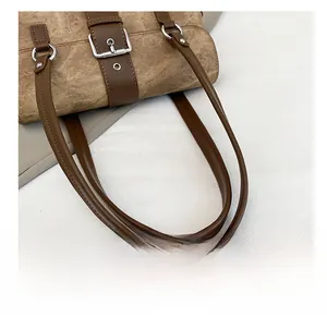 Detail of vintage brown bag showing leather straps, silver rings, and distressed texture