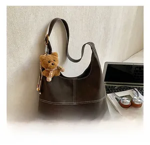 Detail of coffee brown hobo tote with white contrast stitching and cute bear charm