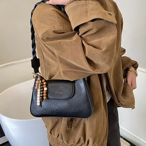 Détail du sac rétro noir avec bandoulière tissée et pendentif en perles de bois colorées