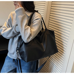Large black travel tote bag shown on model for size and scale comparison