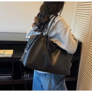 Model wearing a black leather travel tote bag showing its large capacity and soft texture