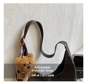 Detail of dark brown suede shoulder bag with contrast stitching and adjustable strap
