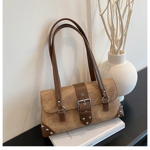 Detail of vintage brown rivet shoulder bag placed on white books with artistic decor