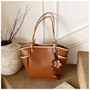 Detail van vintage bruine leren shopper met bloemenhanger en beige biesafwerking