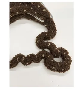 Detail of wavy plush shoulder strap on dark brown polka dot fuzzy tote bag with zipper