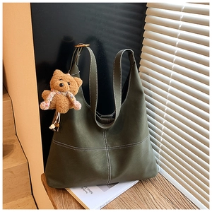 Dettaglio borsa tote verde oliva con cuciture bianche a contrasto e ciondolo a forma di orso