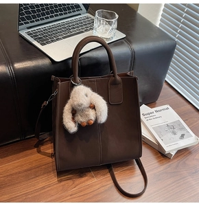 Deep brown tote bag with plush bunny charm near laptop, showcasing daily work style