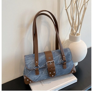 Detail of vintage blue textured underarm bag with leather trim and metal rivets