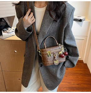 Detailed view of brown quilted leather bag with gold hardware and cherry charm on model