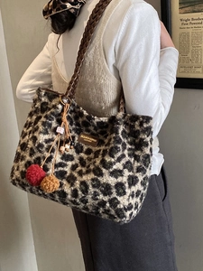 Furry leopard print tote bag with woven leather handles and colorful pompom detail
