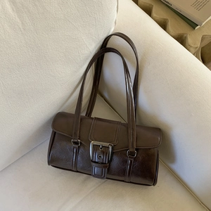 Detailed close-up of dark brown oiled leather bag texture and vintage metal buckle closure