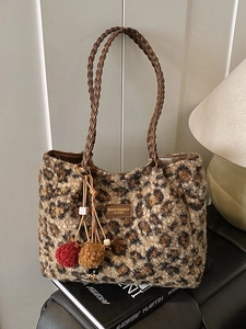 Fuzzy leopard print plush tote bag with brown woven leather handles and pom-poms