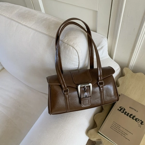 Close-up of retro dark brown faux leather handbag featuring silver buckle and dual straps