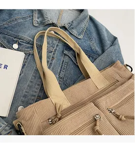 Détail du sac fourre-tout en velours côtelé kaki avec plusieurs poches zippées et anses