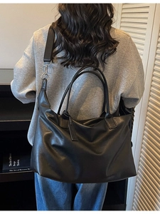 Minimalist black leather travel tote bag with adjustable shoulder strap for women