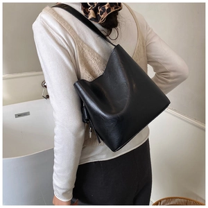 Detail of a black glossy leather bucket bag showing the texture and thin shoulder strap