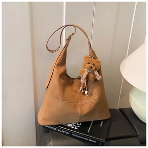 Dettaglio borsa tote in pelle scamosciata marrone con cuciture a contrasto e orsetto